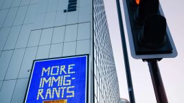An image of a roadside billboard showing the artwork ‘More Immigrants Please’ (2023) by Osman Yousefzada